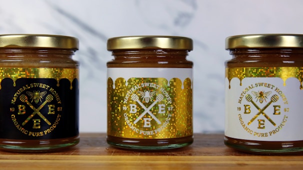 Jars of filtered, pure organic honey lined up on a wooden shelf with natural labels.