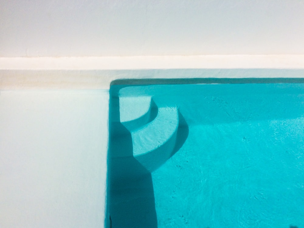 a blue swimming pool with a white wall
