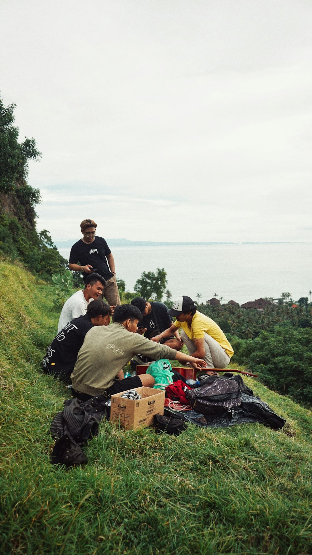 a group of people sitting on a hill with a body of water in the background