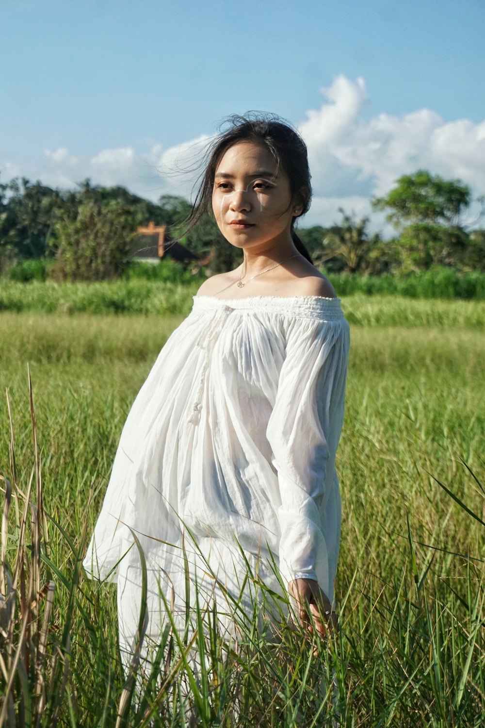 una persona in un vestito bianco in piedi in un campo di erba alta