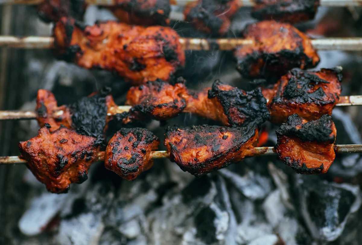 Sate daging sapi bumbu kacang dipanggang di atas arang dengan asap mengepul khas makanan jalanan Indonesia