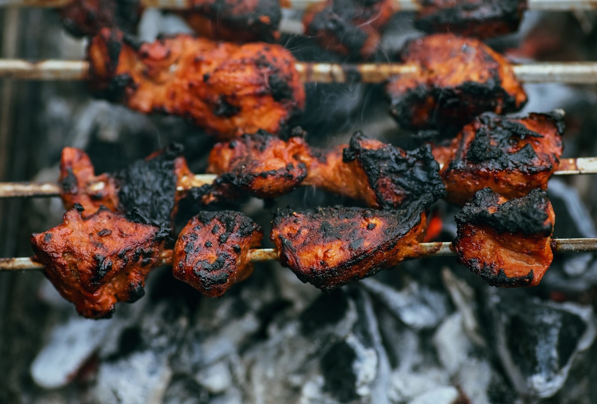 Sate daging sapi bumbu kacang dipanggang di atas arang dengan asap mengepul khas makanan jalanan Indonesia