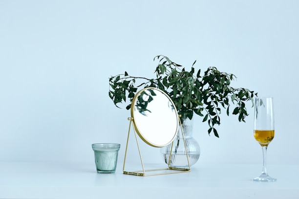 A modern, simple gift set featuring a candleholder, vase, clock, and mirror elegantly arranged on a wooden table.