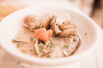 A warm bowl of traditional bean stew with clams, garnished with fresh herbs.