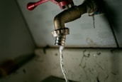 A close-up of hands repairing a leaking faucet with tools.