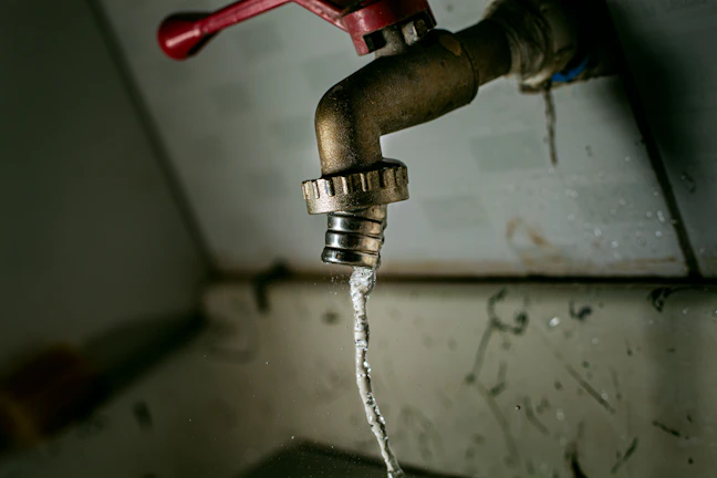 A close-up of a handyman fixing a leaky faucet in a bright bathroom.