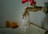 A rusty metal faucet with a red handle is mounted on a wall above a sink. Water is dripping from the faucet, emphasizing a worn or neglected appearance.