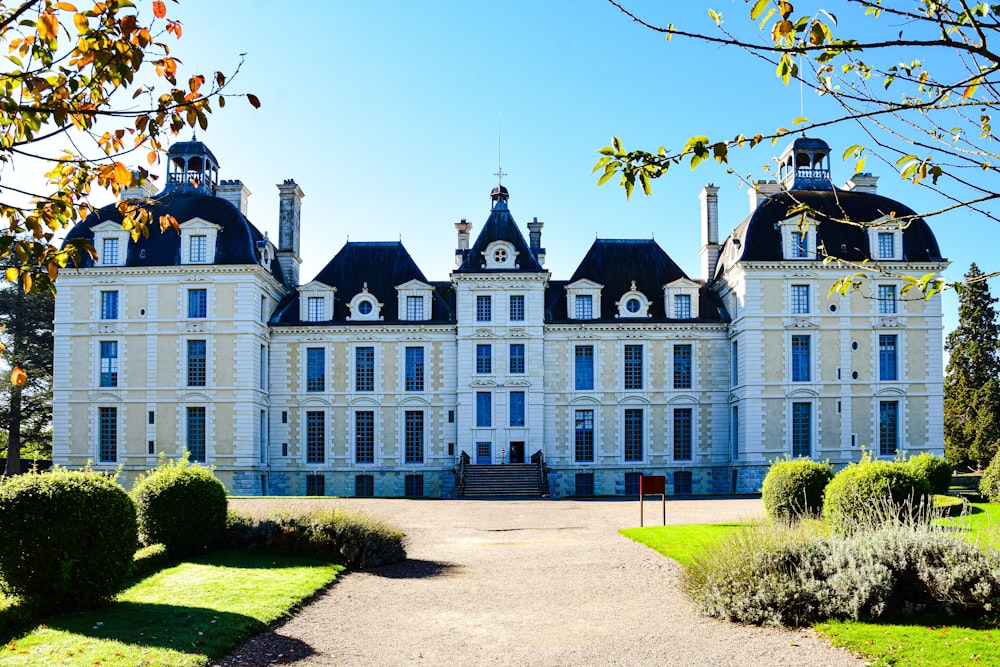 a large white building with a clock tower with Château de Cheverny in the background