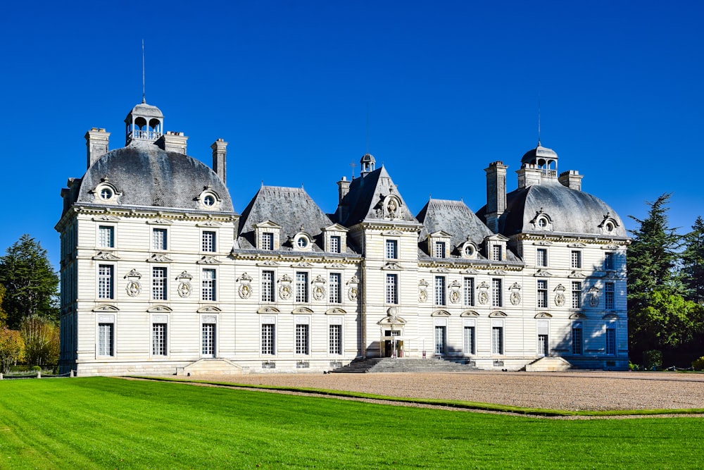 un grand bâtiment blanc avec une pelouse devant lui avec le Château de Cheverny en arrière-plan