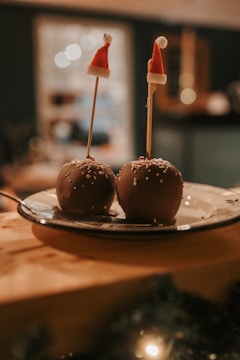 Artisan carefully dipping apples into glossy red candy coating in a cozy kitchen setting.