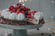 A baker’s hands carefully decorating a chocolate cake with fresh berries and cream.