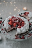 A baker’s hands decorating a cake with fresh berries and cream