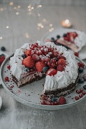A baker’s hands decorating a cake with fresh berries and cream