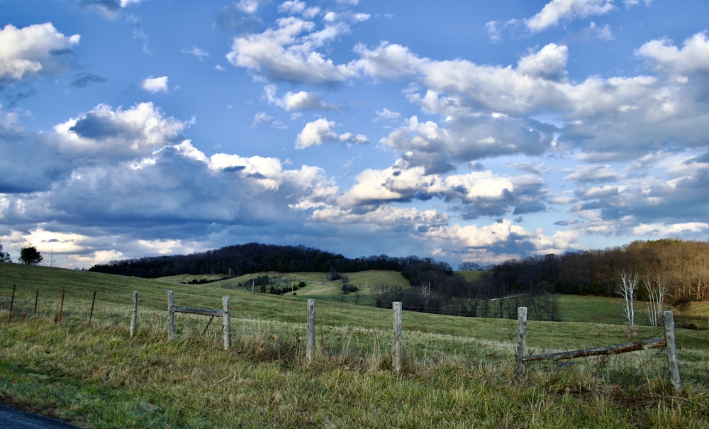 a fenced in field with a cloudy sky above