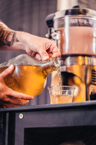 A hand pouring golden bulk concentrate into a measuring cup in a bright studio