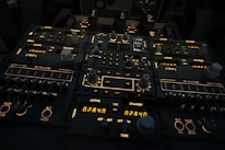 A complex aircraft cockpit control panel with multiple dials, switches, and illuminated displays. The panel features labels such as 'ACTIVE', 'STANDBY', and 'MIC SELECTOR', with various numerical readouts and settings. The ambient lighting is dim, highlighting the glowing indicators and knobs.