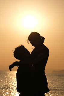 A warm, golden-hour photo of a couple sharing a quiet moment on a beach, the soft waves gently rolling behind them.