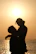 A romantic couple embracing during a golden sunset on an Oahu shoreline.