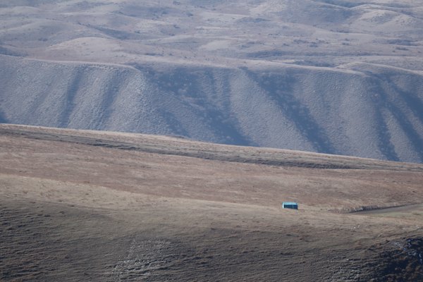 A blue car driving through a desert — Karakol, Kyrgyzstan