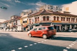 A SpeedParcel delivery van speeding through Kuala Lumpur city streets under a clear blue sky.