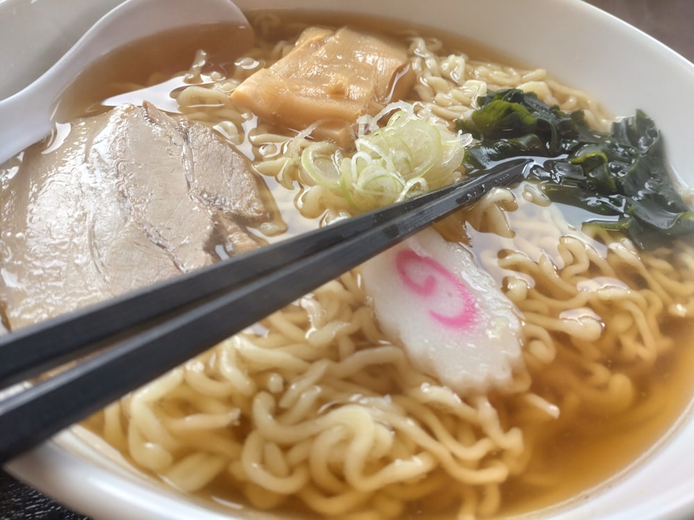 a bowl of noodle soup with chopsticks