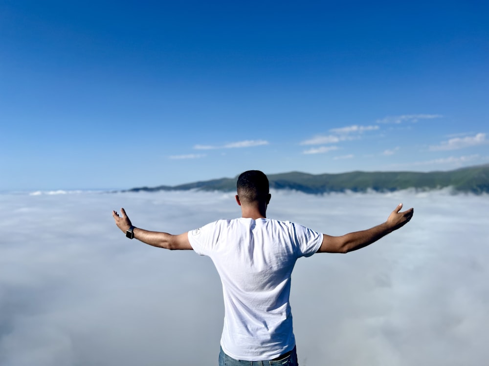 a man standing in front of a body of water with his arms out