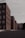 A series of modern, rectangular buildings with a uniform architecture line a quiet, empty street. The buildings are mostly composed of red brick with large glass windows, and the overcast sky adds a muted tone to the scene. A sign with the word 'BÖRSE' is visible at the top of one of the buildings.