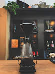 A modern open box coffee maker displayed on a kitchen counter with natural morning light.