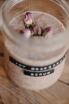 A collection of colorful body scrubs in glass jars with wooden spoons.