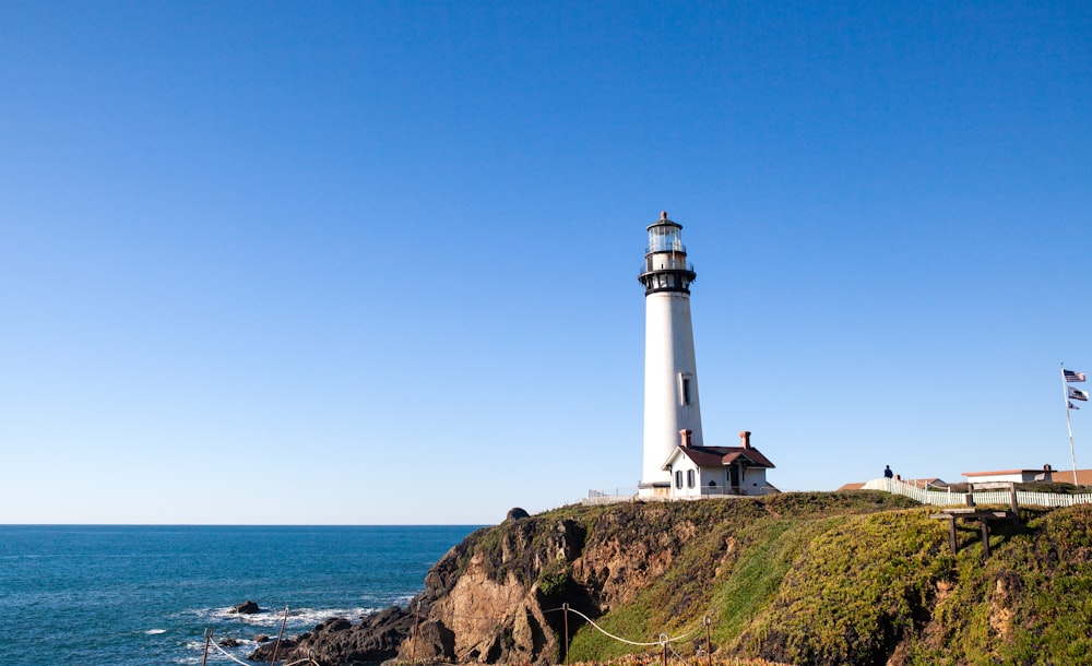 a lighthouse on a hill by the water