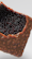 A close-up view of a partially opened chocolate bar filled with dark, glossy spheres that resemble caviar. The chocolate has a textured surface with a milky brown color, while the spheres are dark red to black and appear shiny.