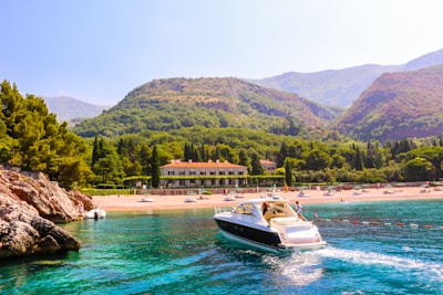 A vibrant coastal view of Albania's turquoise sea with a yacht sailing near the shore.