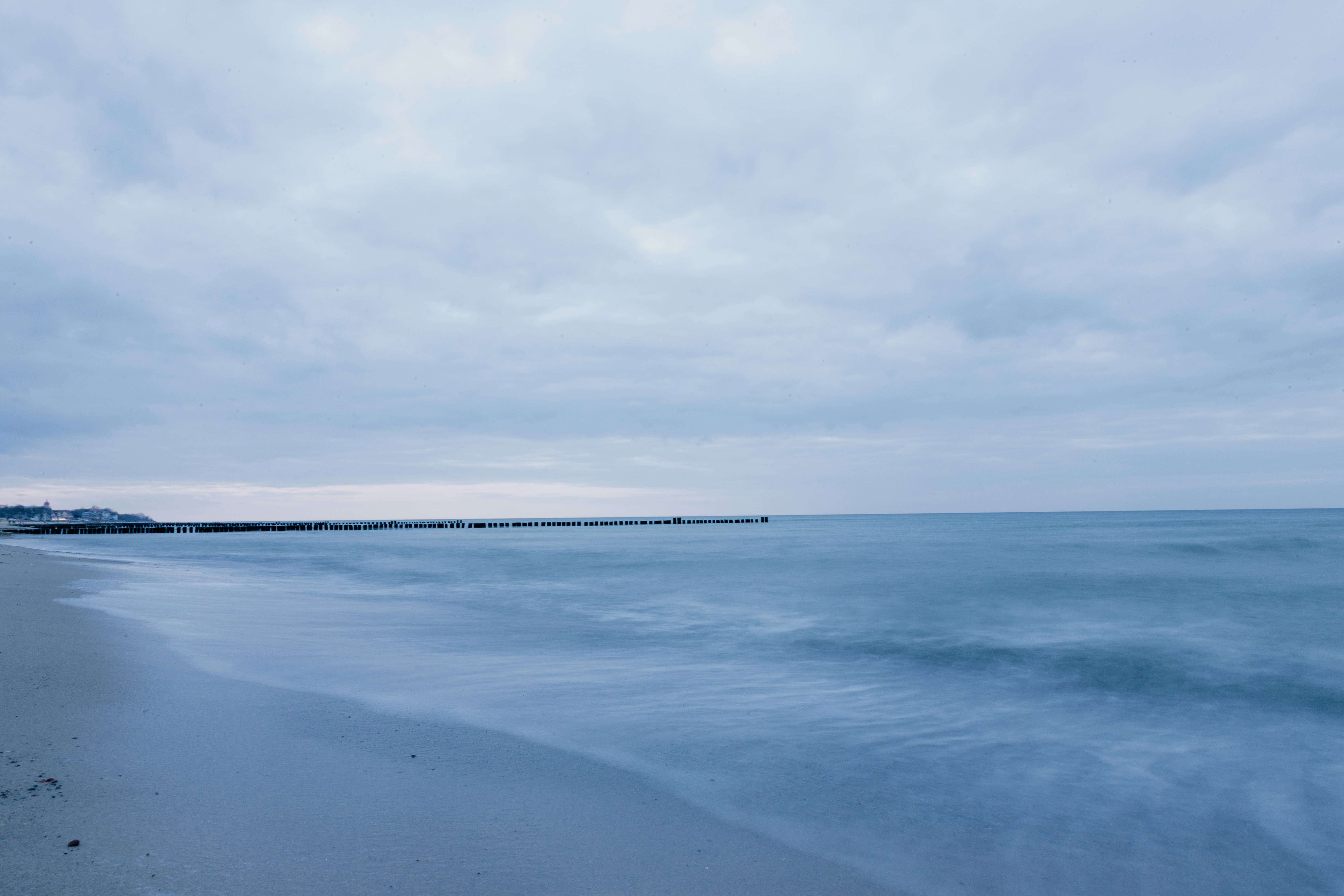 a beach with a pier in the distance