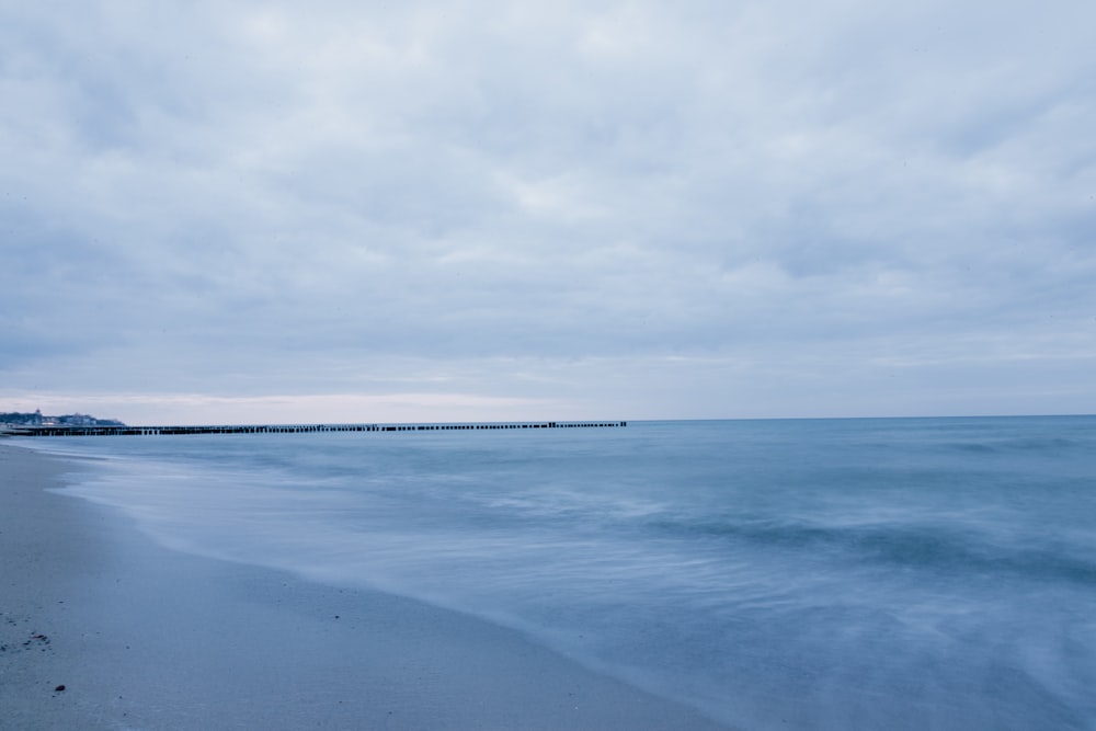 a beach with a pier in the distance