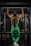 A person is performing a pull-up in a gym, wearing a matching green athletic outfit. The setting includes typical gym equipment with a focus on the muscular back and arms of the individual.