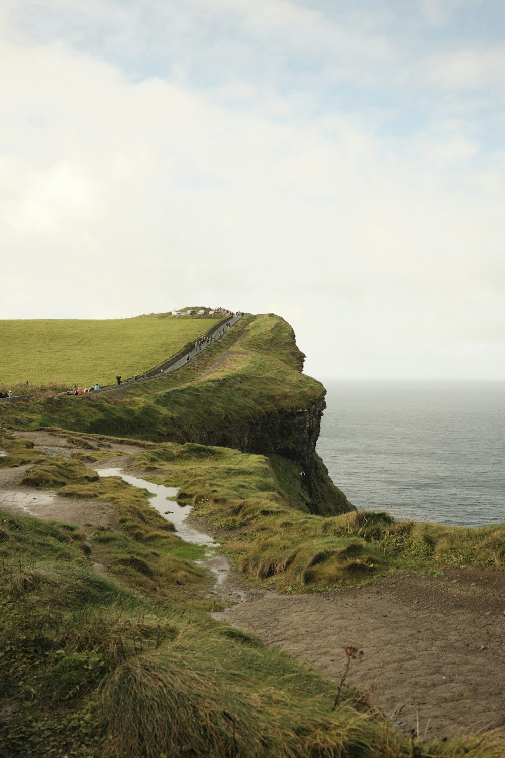 a cliff side with a road and a body of water below