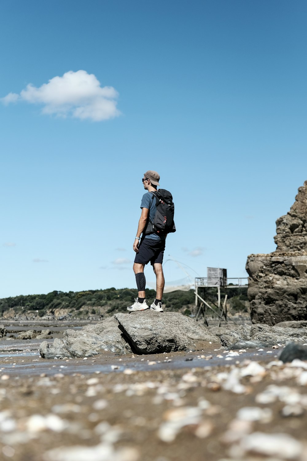 Un uomo con uno zaino in piedi su una spiaggia rocciosa