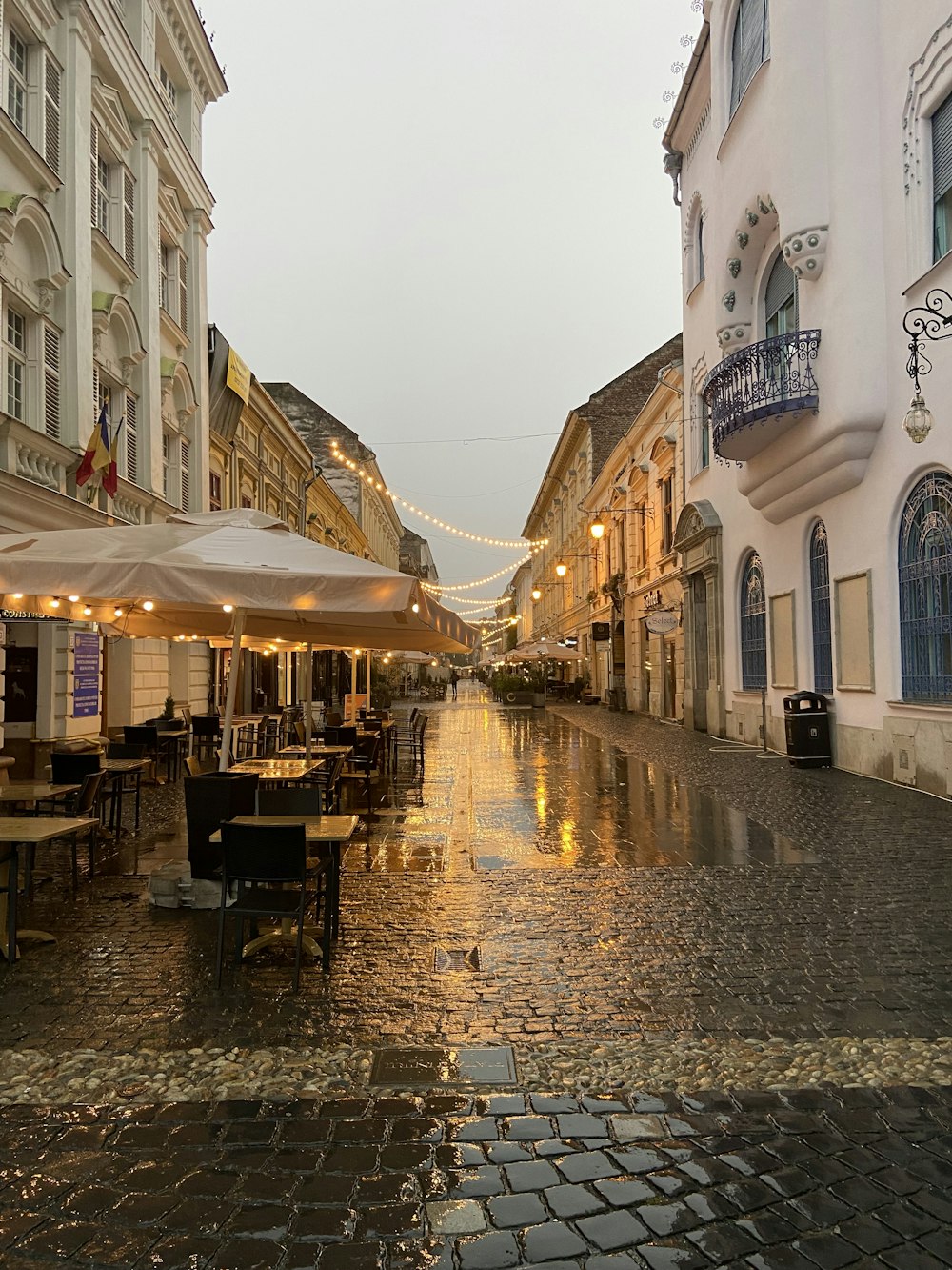 uma rua molhada com mesas e cadeiras