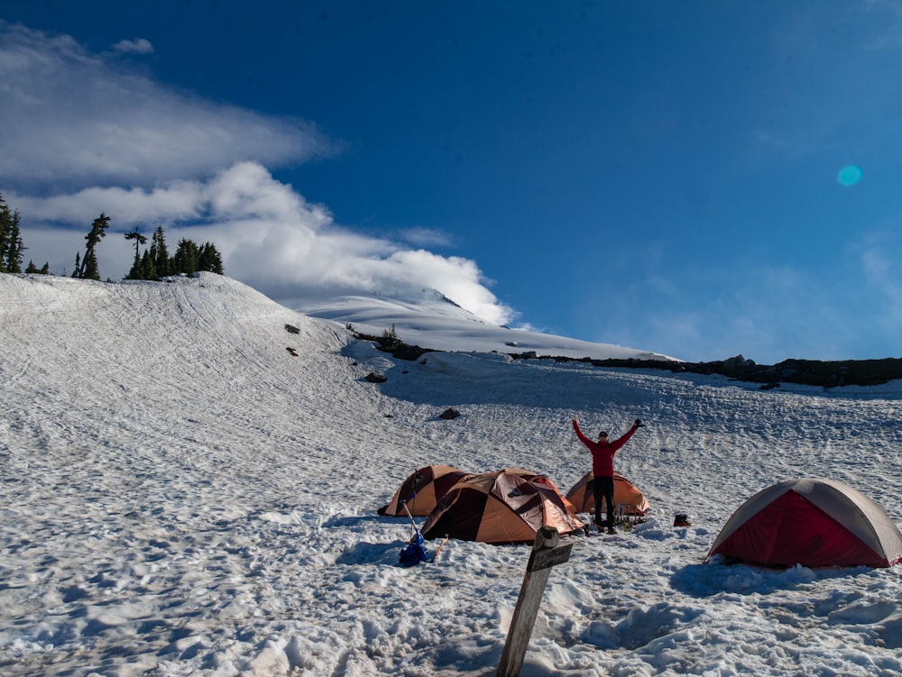 a person lying on the snow next to a tent