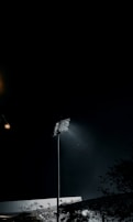 A row of LED floodlights lighting up a sports field during an evening game.