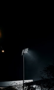A powerful flood light illuminating a large outdoor sports field at dusk.