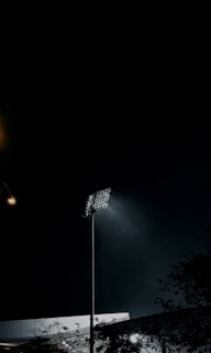 A row of LED floodlights lighting up a sports field during an evening game.