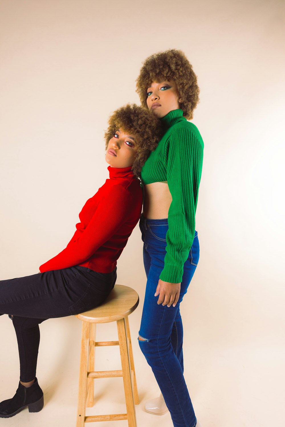 a woman standing next to a man sitting on a stool