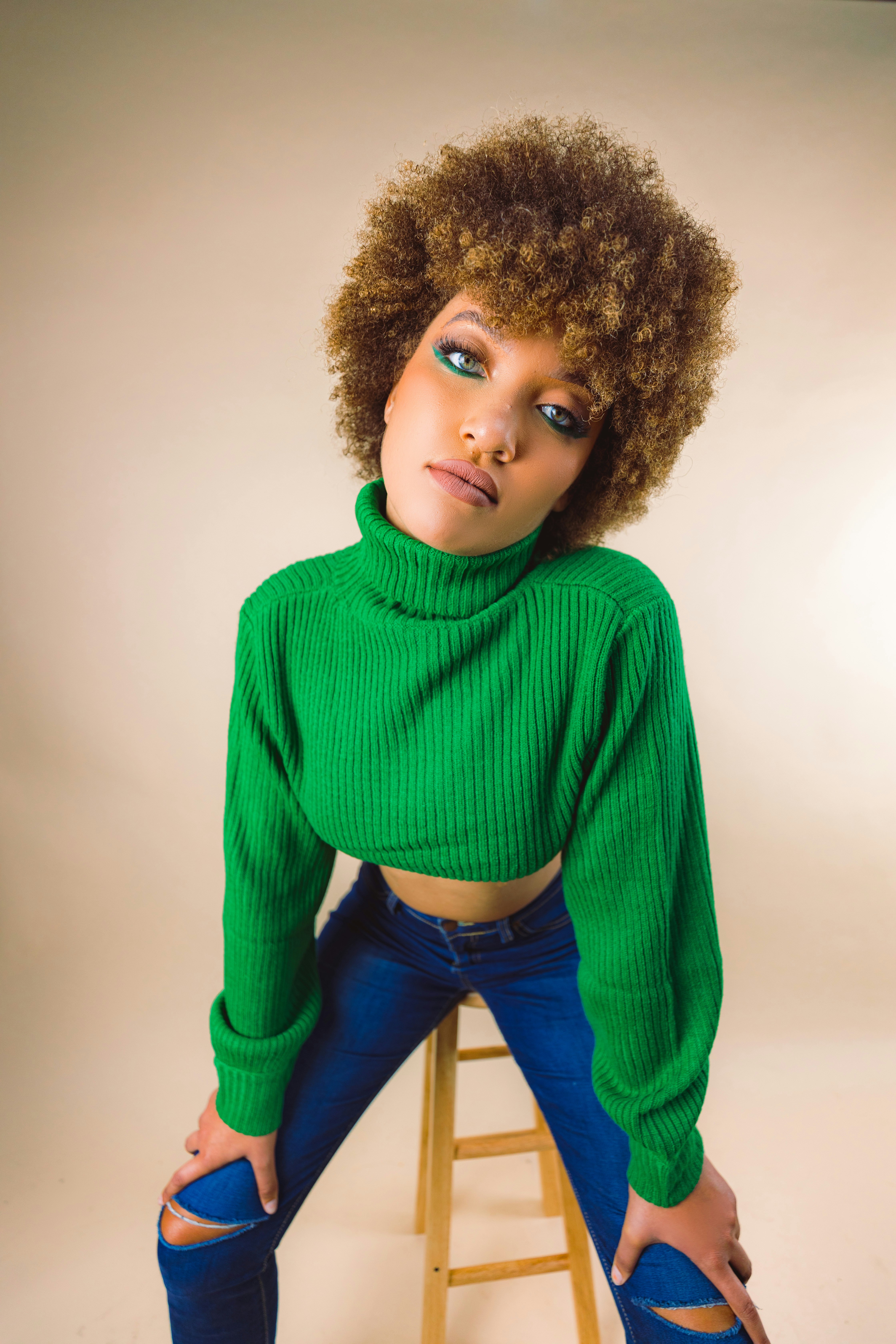 a young girl with curly hair sitting on a chair