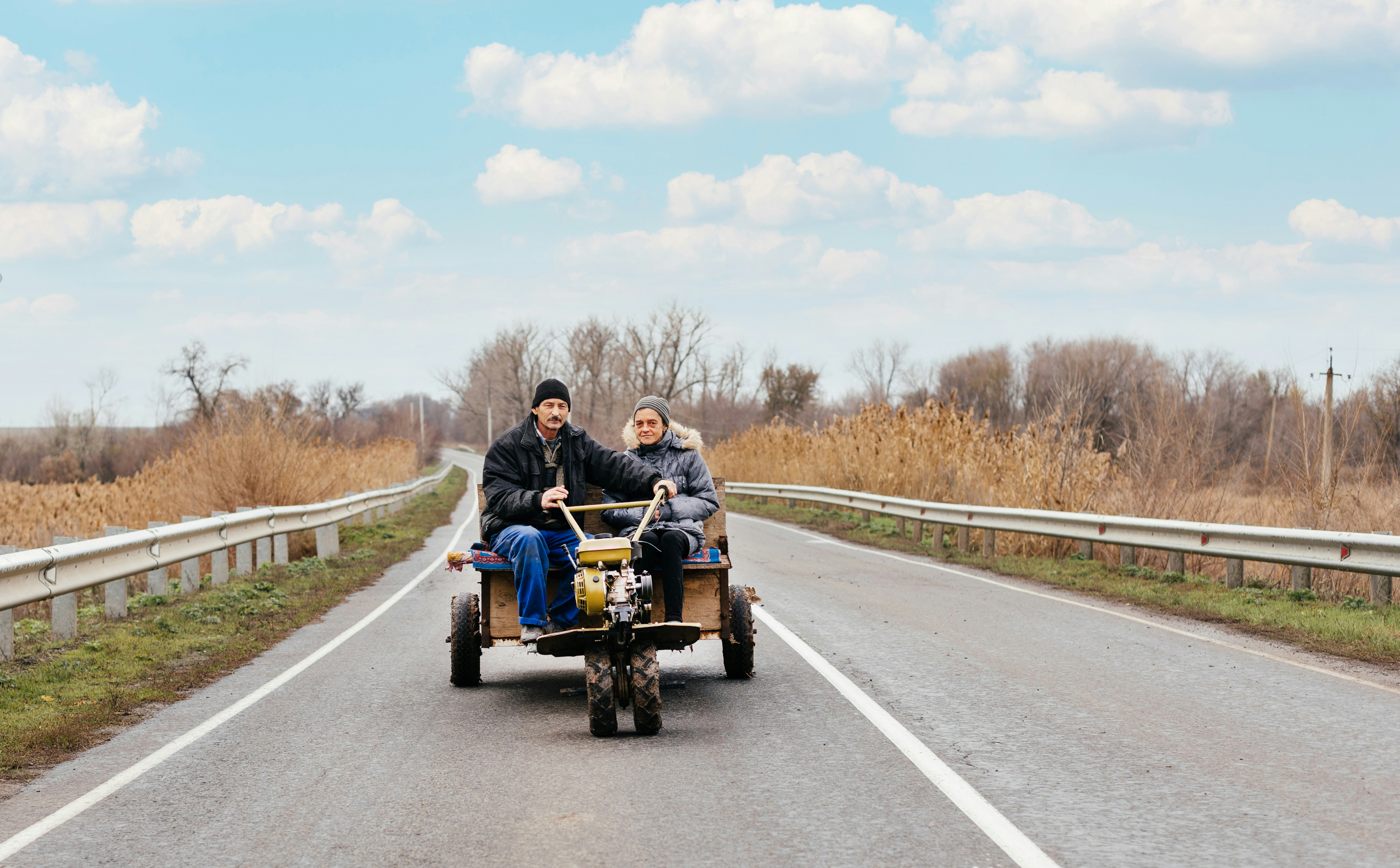 a man and woman driving a vehicle on a road
