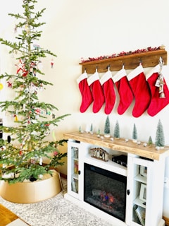 A mantelpiece decorated with stockings, garlands, and glowing candles creating a warm holiday atmosphere.