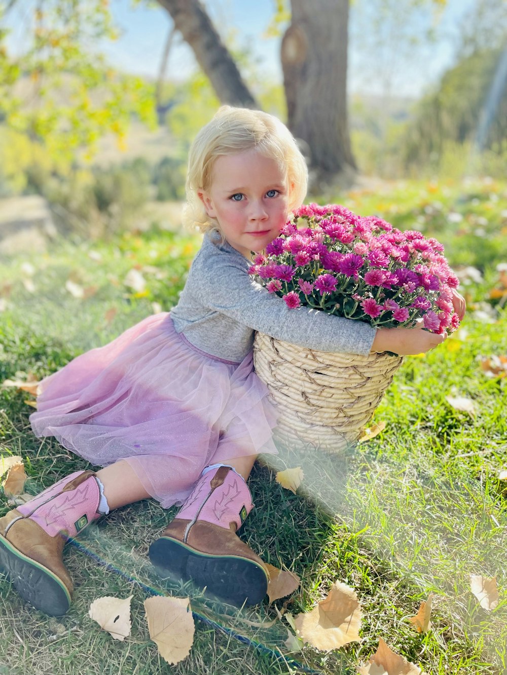 a girl sitting in grass holding flowers