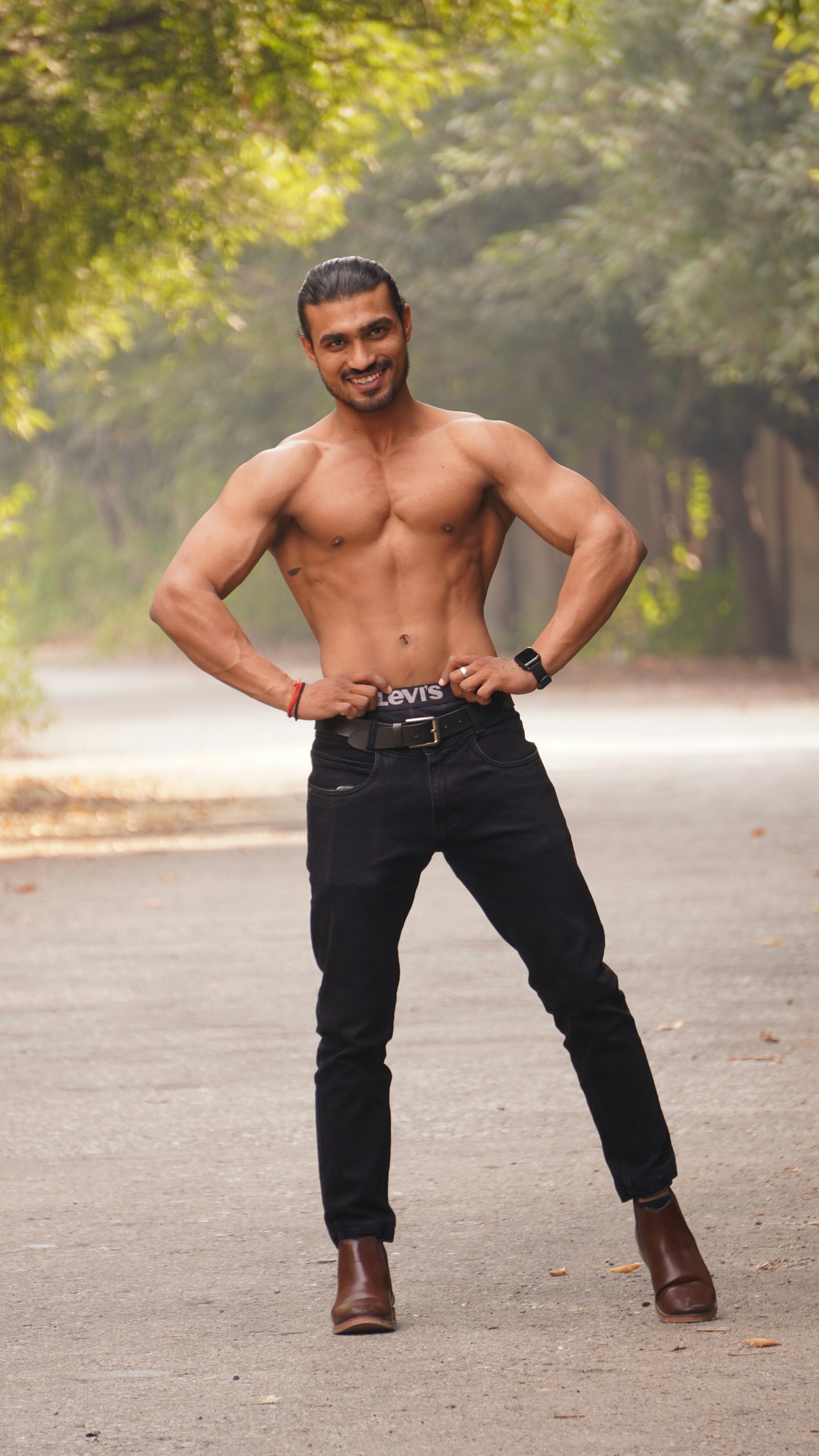 Athletic man showing muscle definition, outdoor setting, confident expression