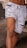 A well-defined muscular leg wearing light blue, distressed denim shorts with frayed edges and a drawstring.