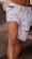 A well-defined muscular leg wearing light blue, distressed denim shorts with frayed edges and a drawstring.